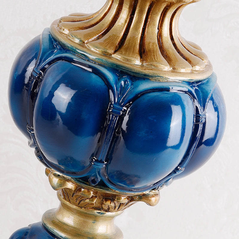 Close-up of glossy blue and gold resin lamp base with curved spherical body detail