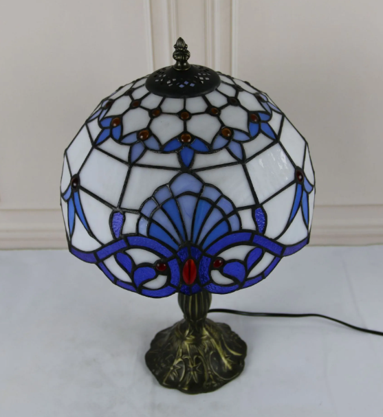 Stained glass bedside table lamp close-up with blue flower motifs and dark bronze base