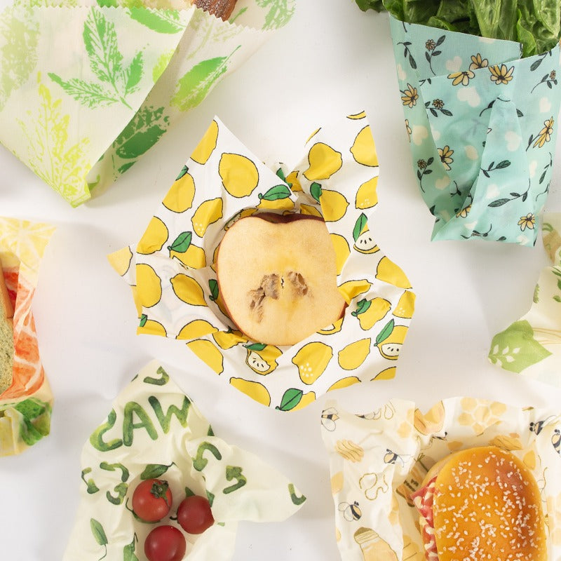 Assorted fruit-pattern reusable beeswax food wraps, laid flat on a table