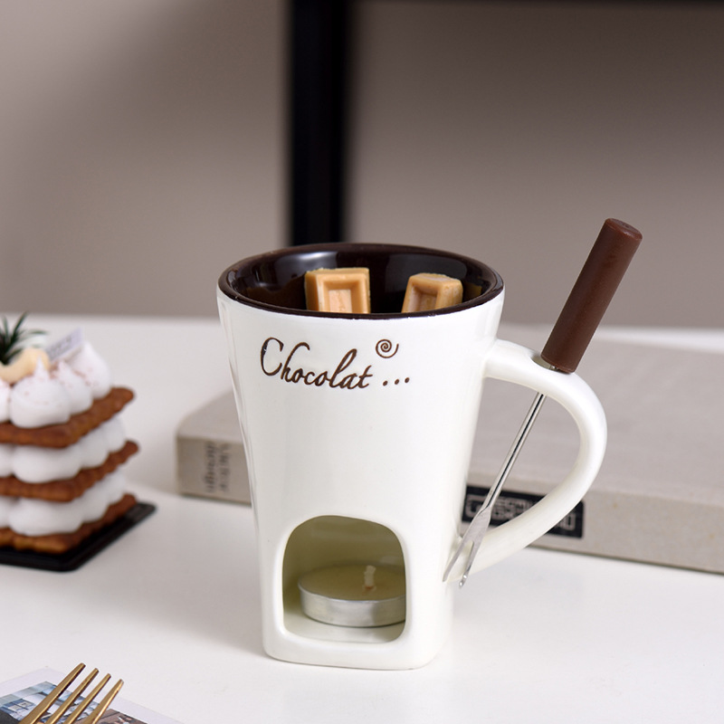 White mini fondue mug with wooden handle, metal fork, and lit warmer base