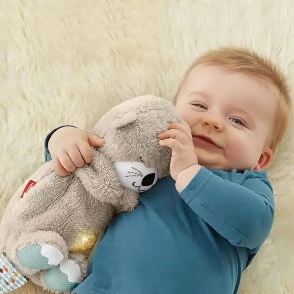 Baby holding a gray plush bear with glowing belly light while smiling