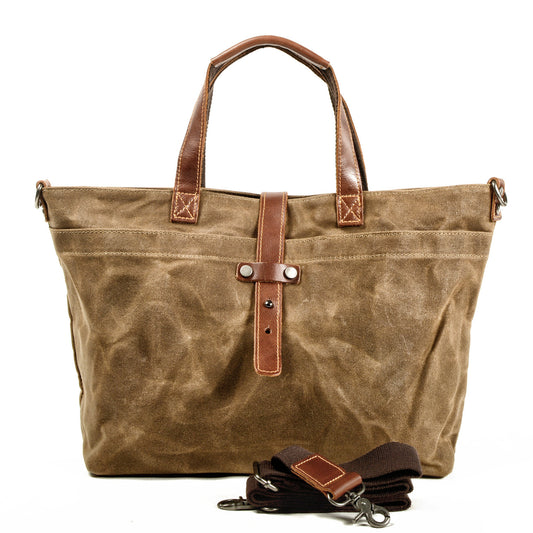 Large canvas tote bag with leather handles, front strap detail, and key fob accessories