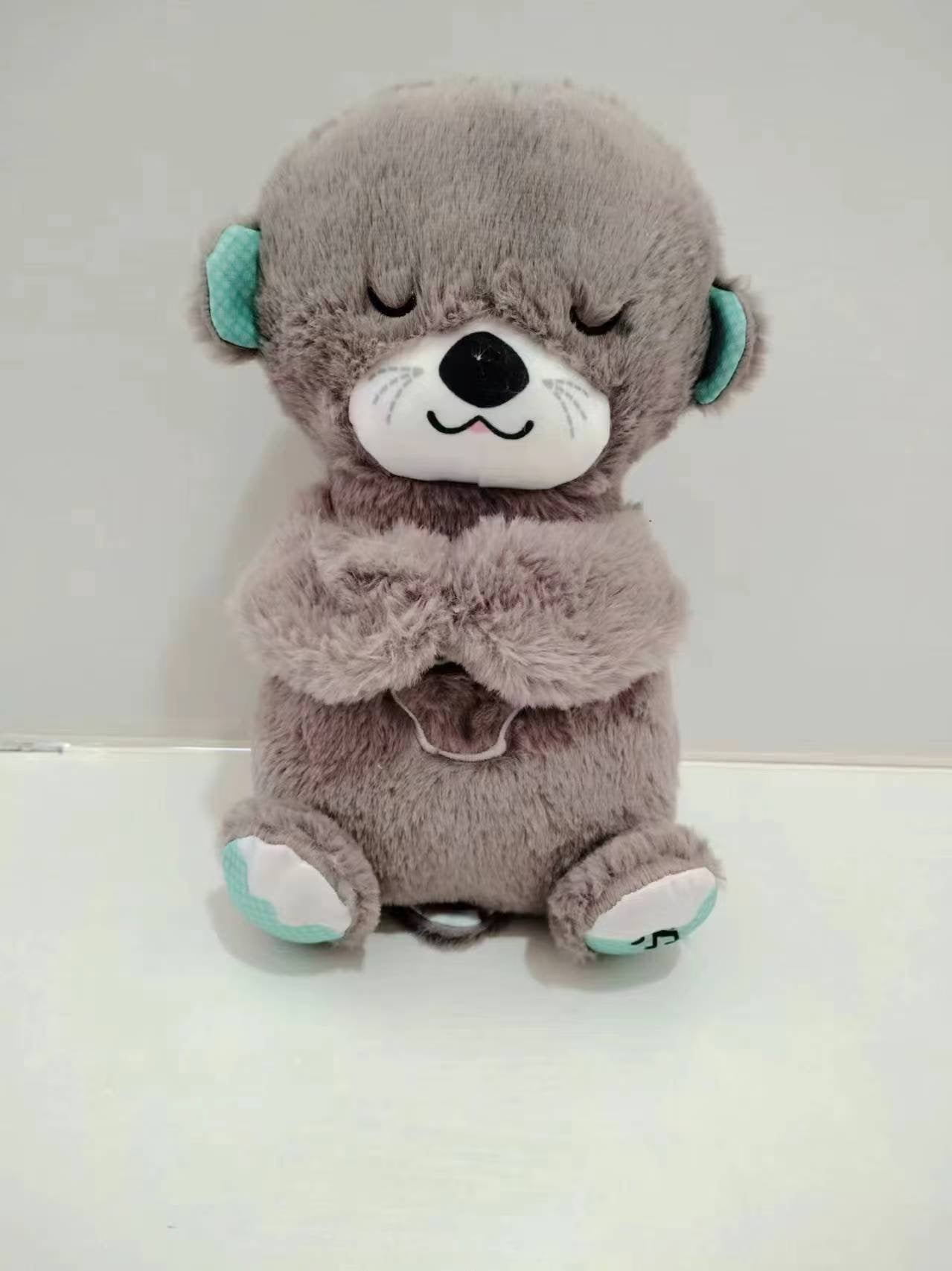 Brown otter plush baby sound machine with turquoise ear accents and closed eyes.