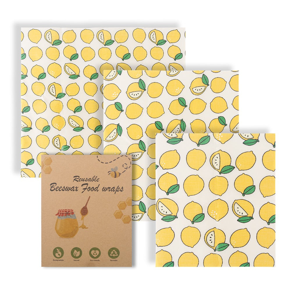 Three-piece reusable beeswax food wraps in repeating lemon print, in branded sleeve