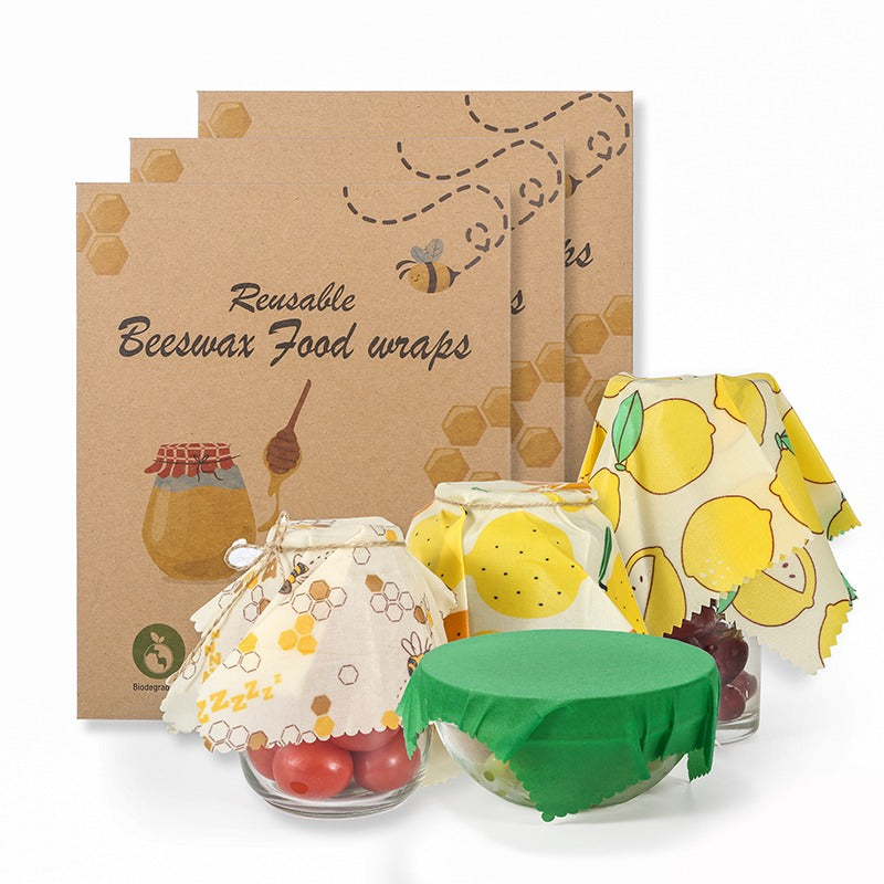 Three reusable beeswax food wraps with honeycomb print, lemons, and assorted patterns