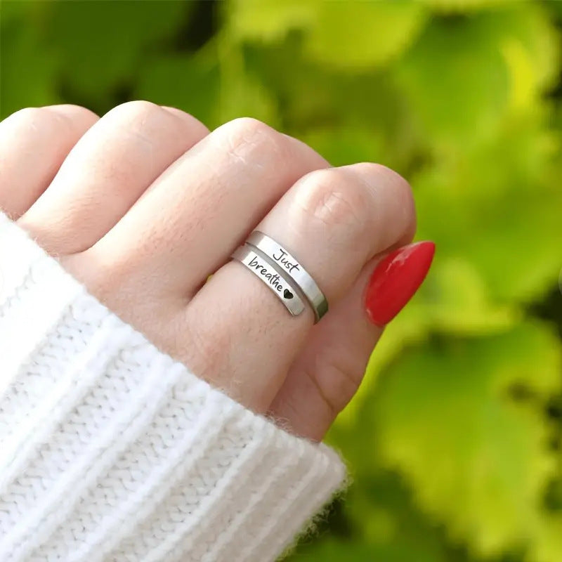 Stainless steel heart ring engraved "Just breathe" worn on hand