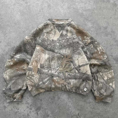 Oversized camouflage hoodie laid flat, hooded neckline and long sleeves visible.