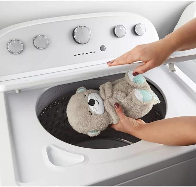 Gray plush otter sound machine with glowing belly light, held for baby play