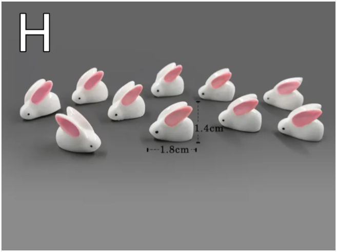 Small white rabbit resin figurines with pink inner ears arranged in a group.