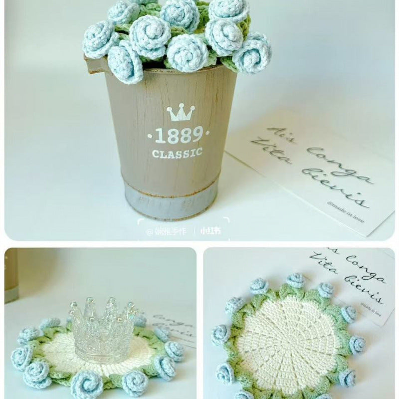 Crocheted coaster with pale center and light blue rose border, green filler stitches