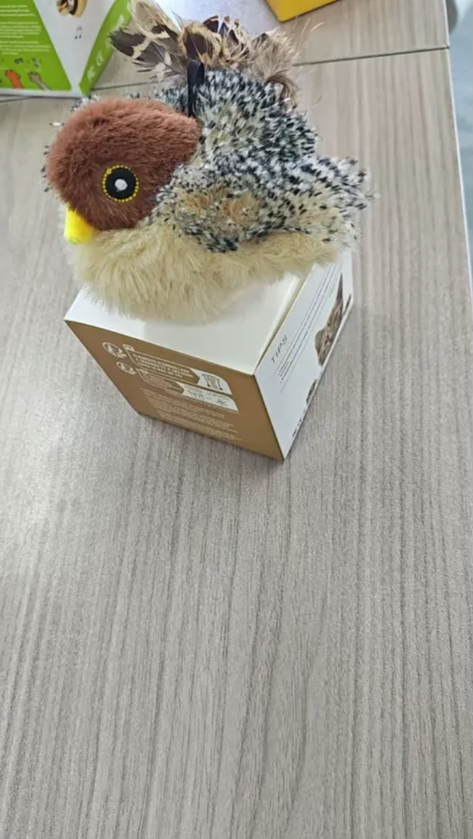 Plush bird cat toy with speckled gray wings and brown head, lying in a box