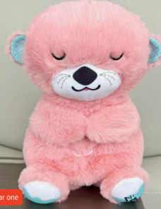 Pink plush bear sleep aid with closed eyes, embroidered nose, blue ear and paw accents