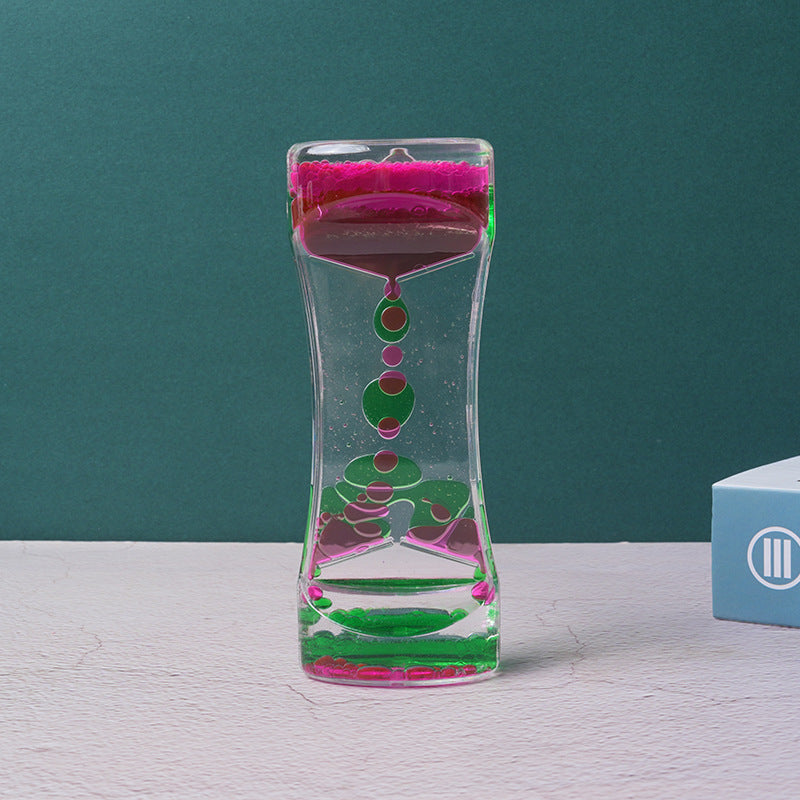 Two-color liquid hourglass timer with magenta top and green bottom, floating colored beads