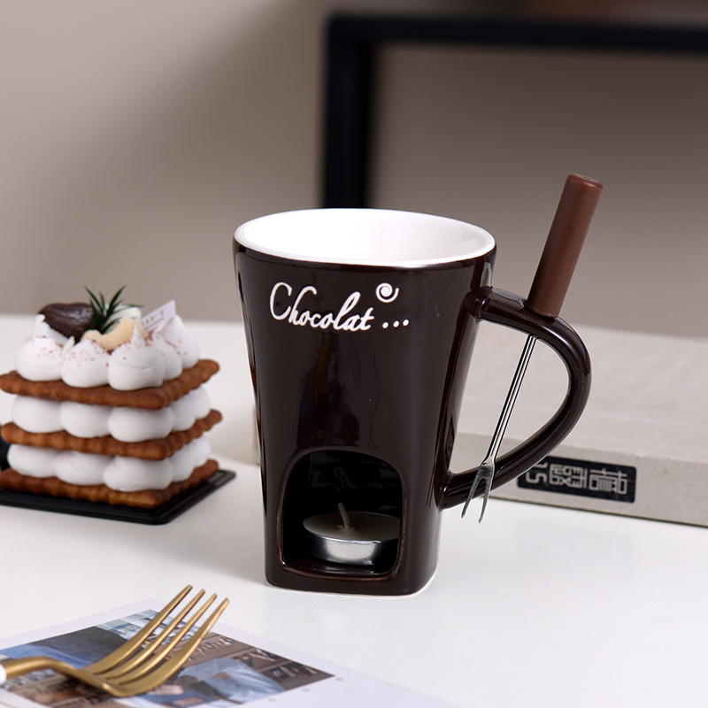Dark mini fondue mug with wooden handle, metal fork, and lit warmer base