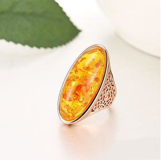 Oval amber statement ring with yellow resin center and ornate perforated metal shank
