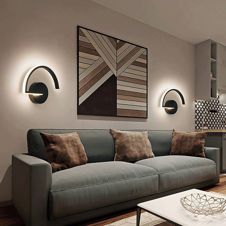 Black LED wall sconce with circular backplate and curved light bar