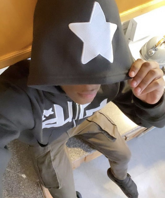 Gray zip-up hoodie worn by model, white star applique on hood and central zipper front.