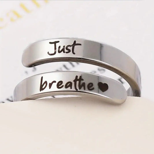 Silver engraved ring showing "Just" and "breathe" with heart icon detail