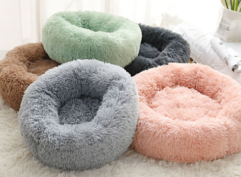 Round plush pet bed donut nest with raised bolster rim, shown in several colors.