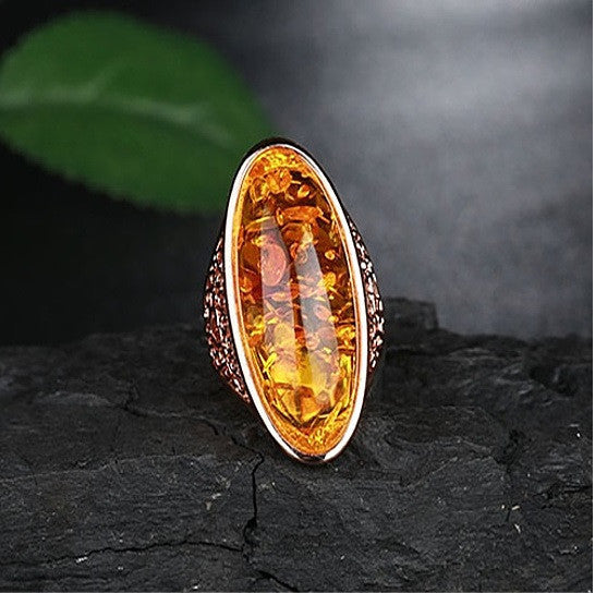Oval amber statement ring with fiery resin center and black-textured halo, silver-tone band