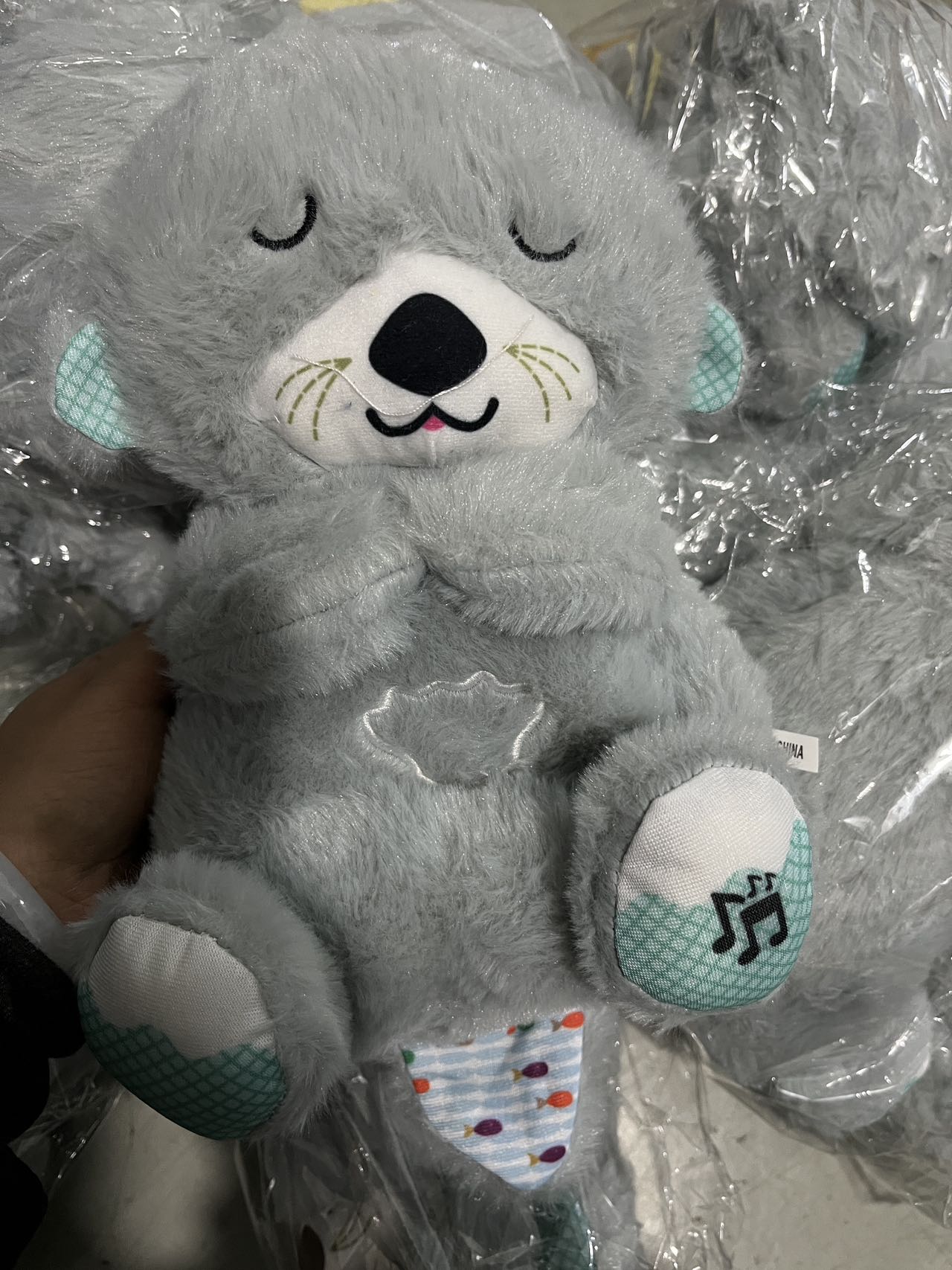 Gray plush koala baby sound machine with closed eyes and musical paw patch