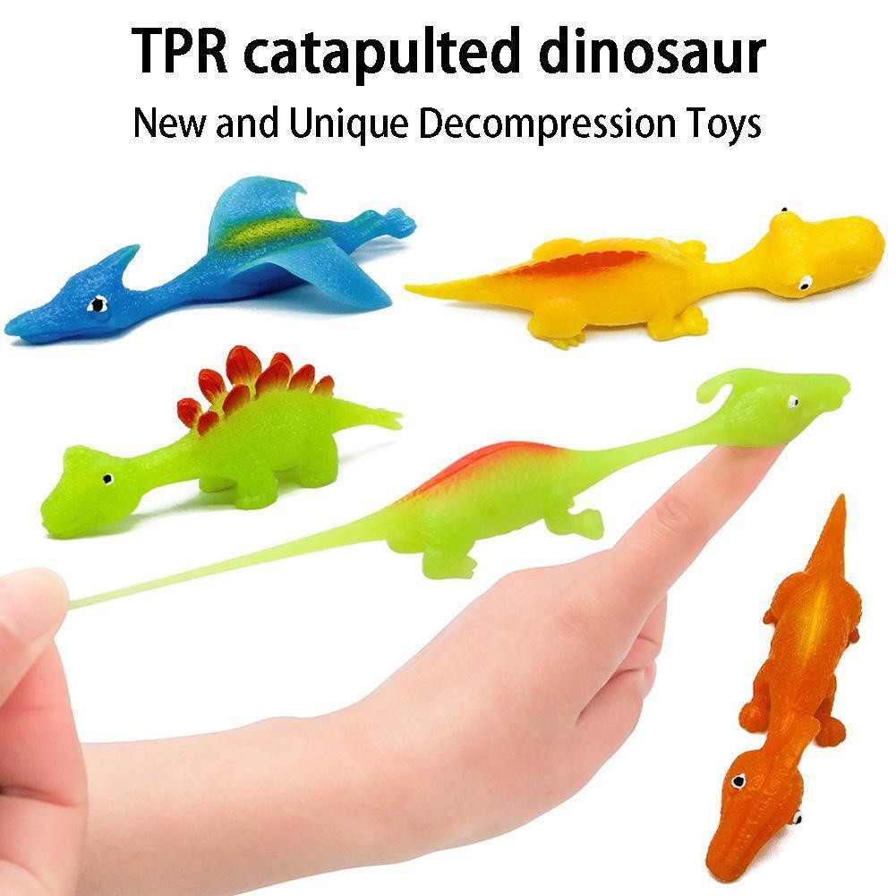 Multiple dinosaur slingshot finger toys in blue, yellow, green, and orange