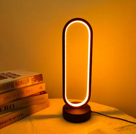 Black oval LED table lamp glowing warm orange with round base