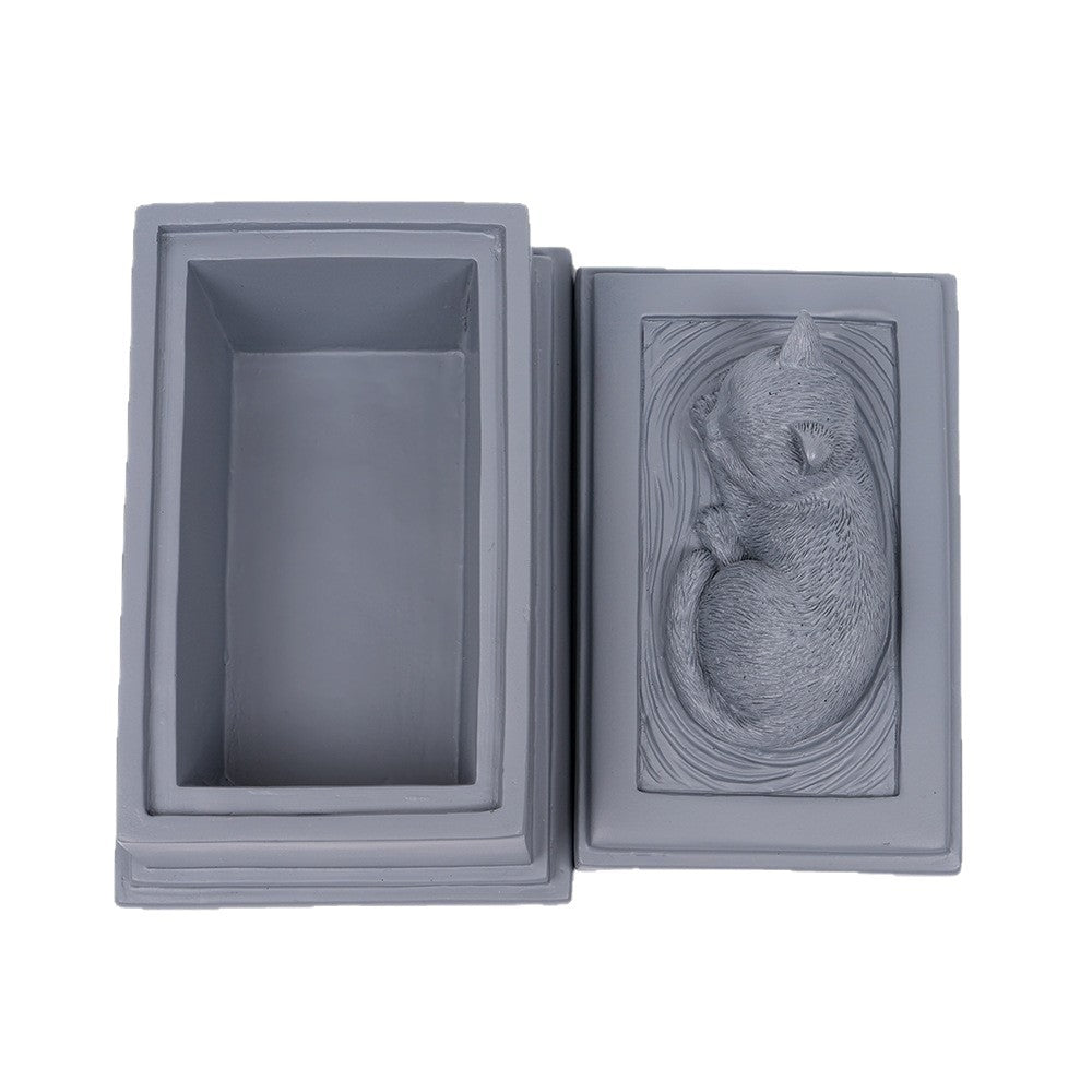 Gray square resin pet memorial urn open for viewing, with gold paw emblem panel