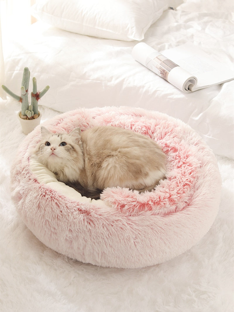 Plush pet bed with raised rim and tunnel opening, pink fluffy interior.
