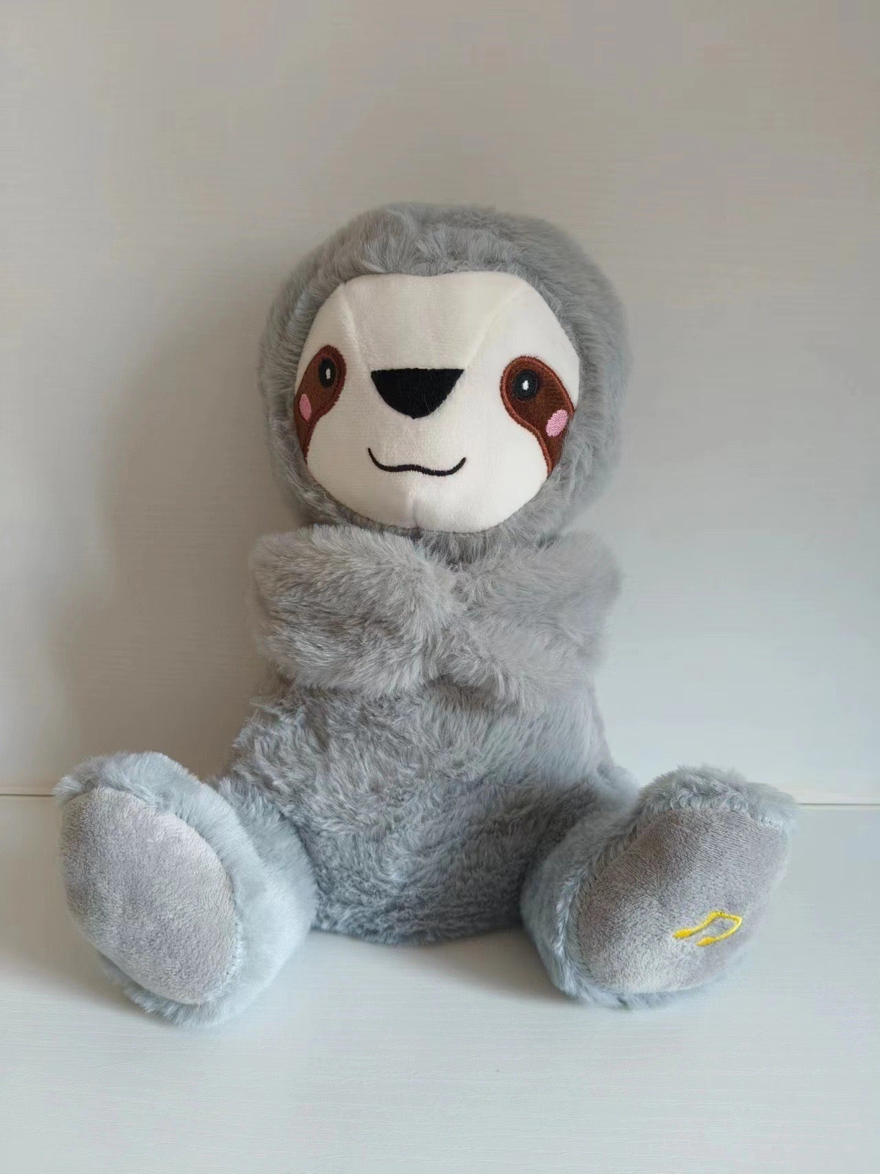Gray penguin plush baby sound machine, white face panel and stitched smile.
