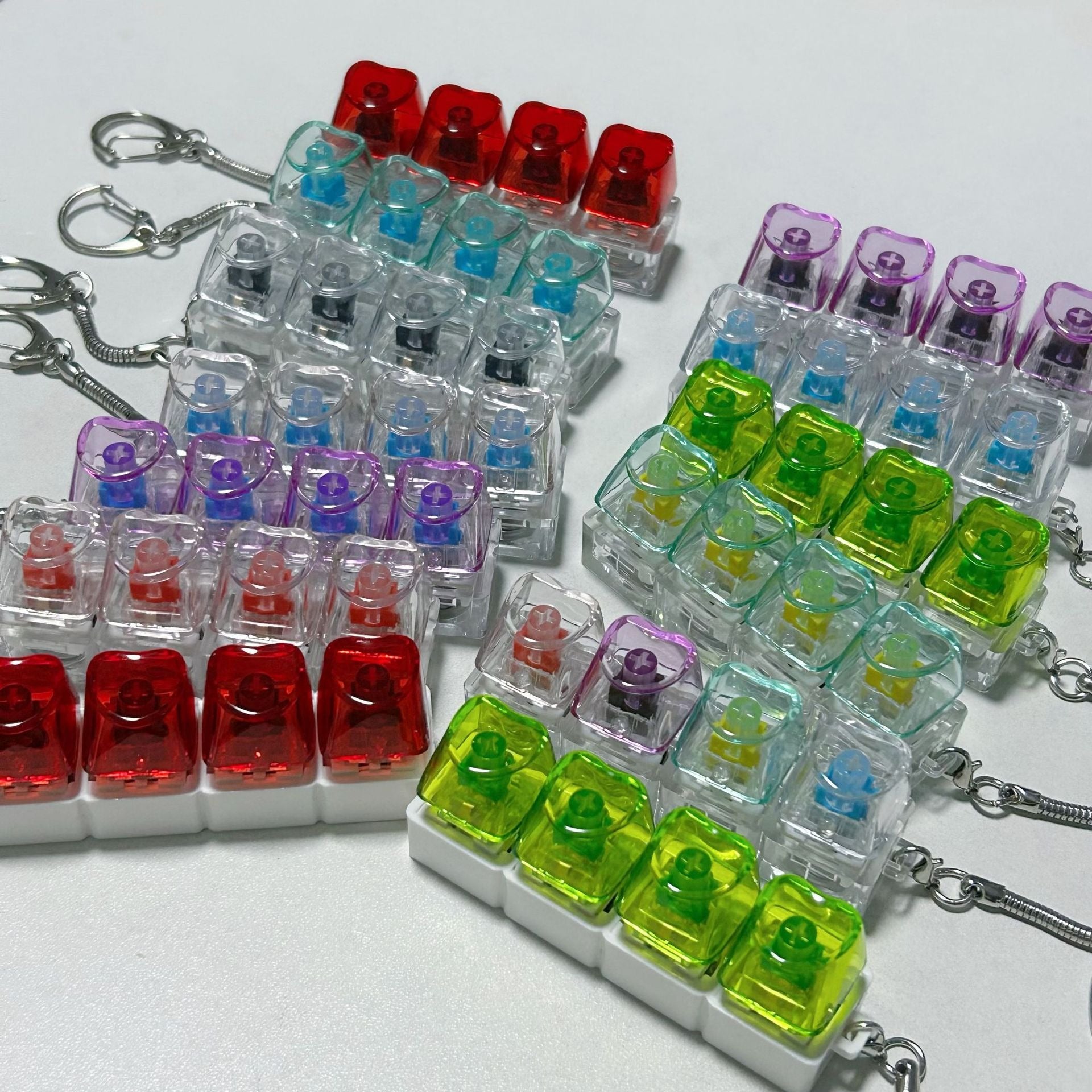 Many transparent light-up shaft tester fidget toy keychains arranged on a white surface