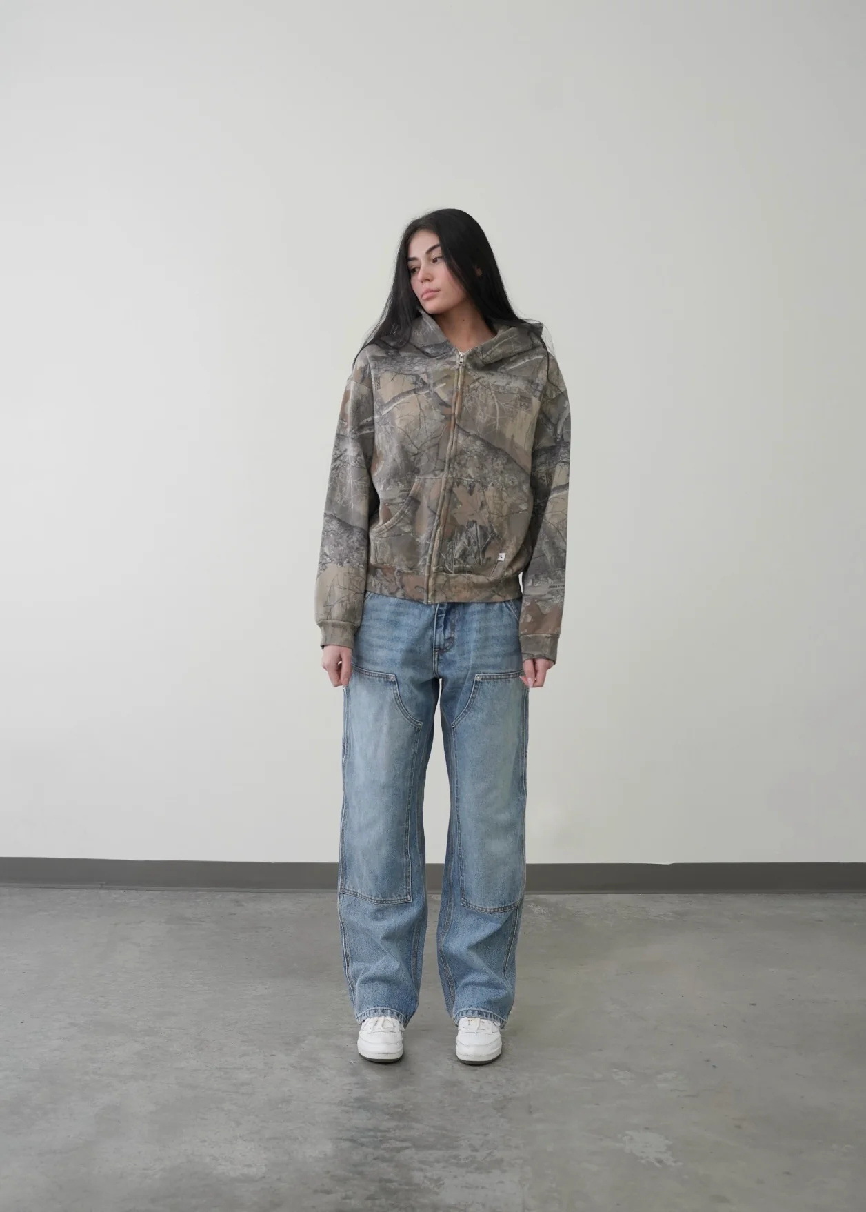 Camouflage zip-up hoodie on model, attached hood and front zipper, gray tan print