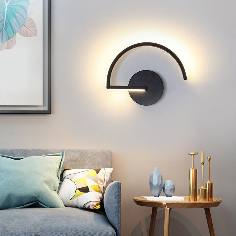 Black LED wall lamp with curved arched light and round backplate, warm glow on wall.