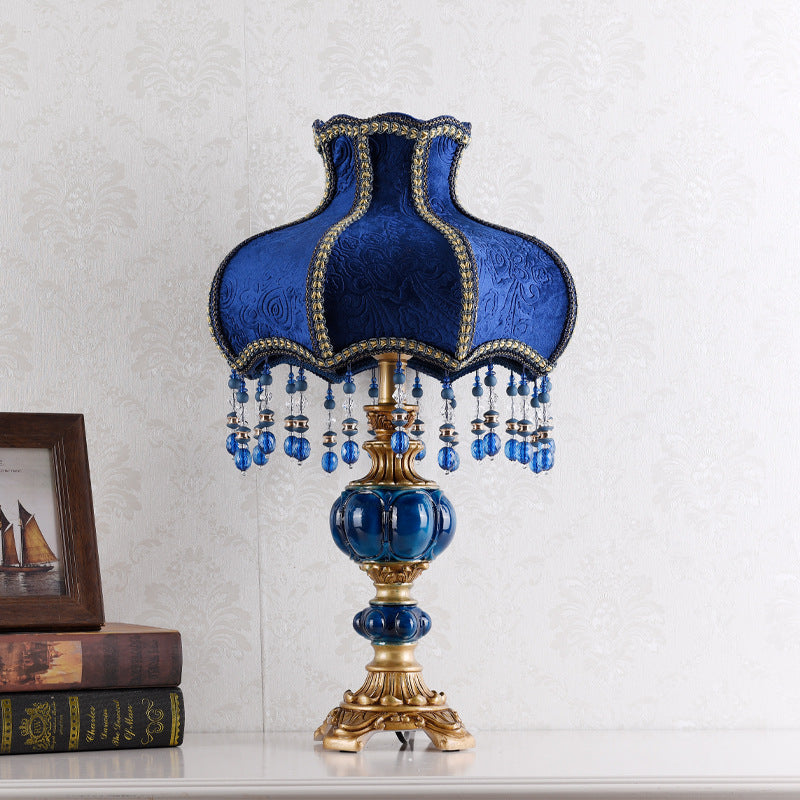Blue ornate table lamp with textured fabric shade, gold trim, and hanging crystal bead strands