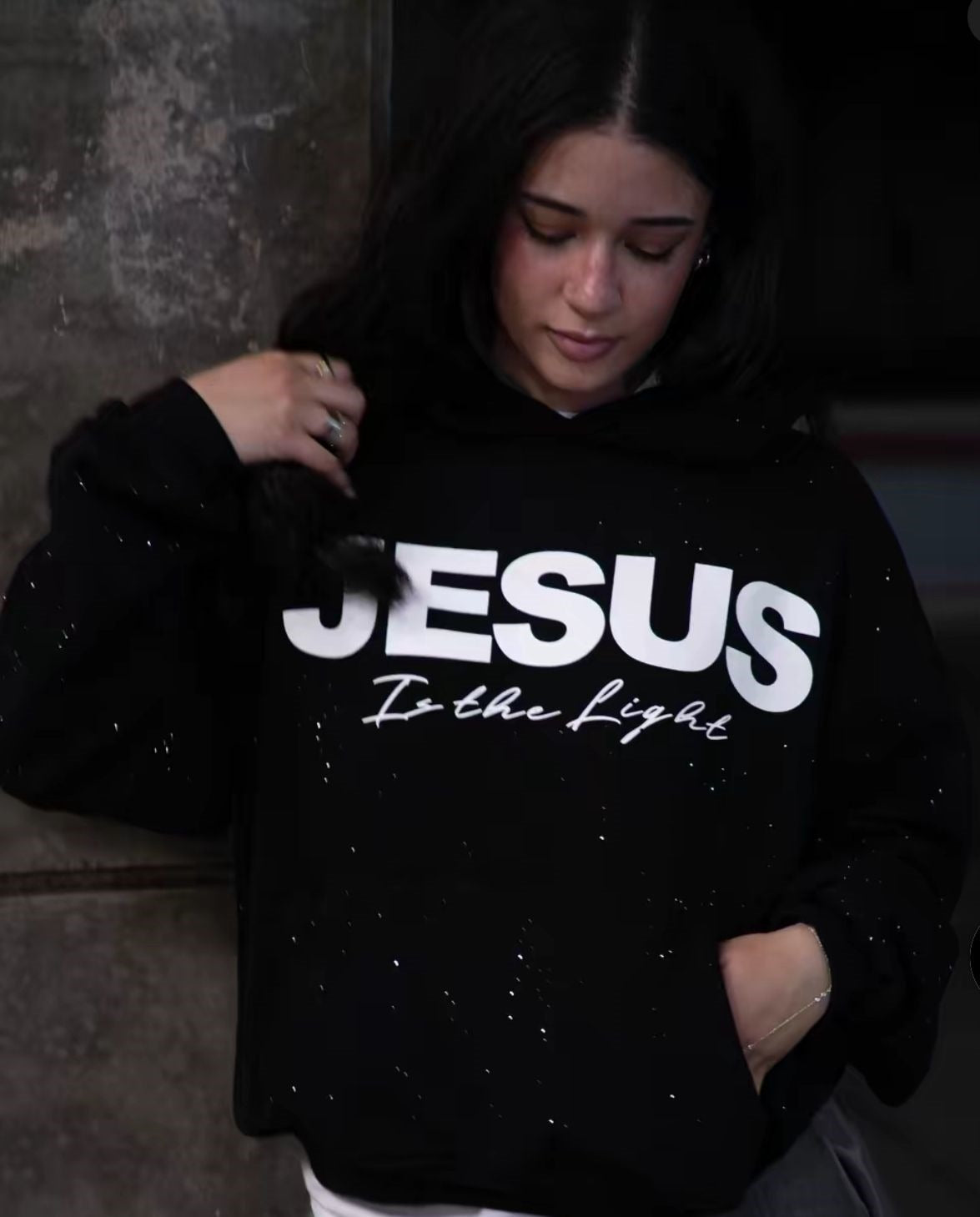 Black pullover hoodie with white “JESUS” front graphic and drawstring hood