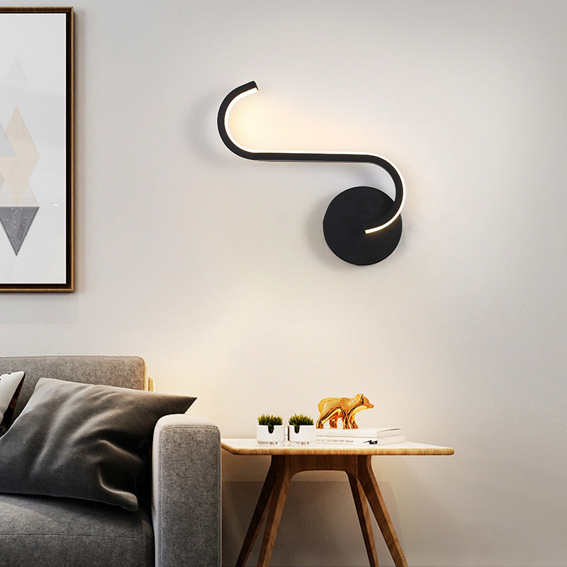 Black LED wall sconce with long curved light tube and round backplate, warm glow.