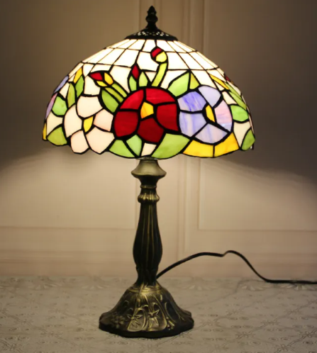 Stained glass bedside table lamp with white shade, green panels, and red center