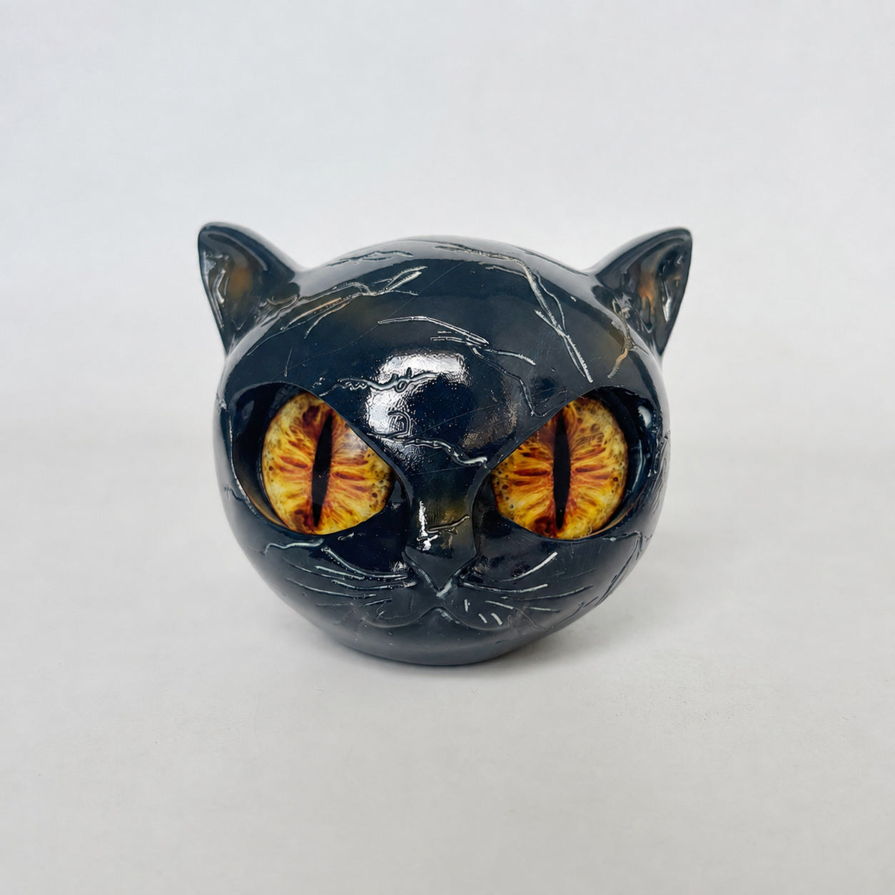 Black resin cat sculpture ornament with amber-yellow eyes, glossy reflective surface