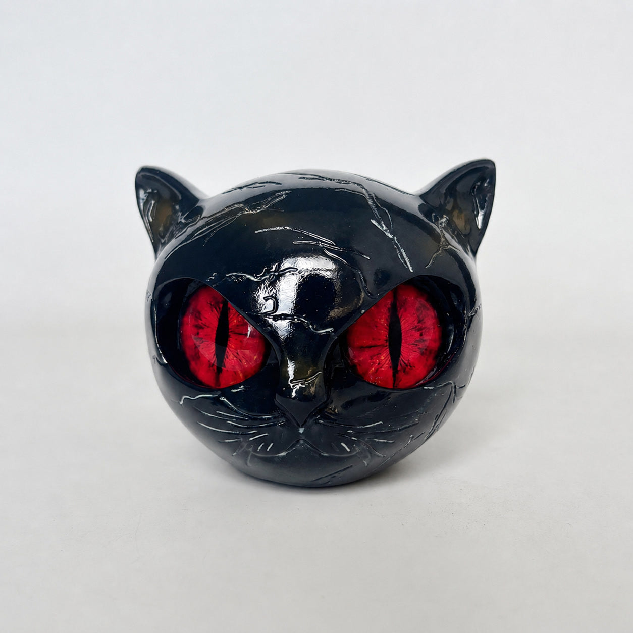 Black resin cat sculpture ornament with red-glossy eyes, reflective finish