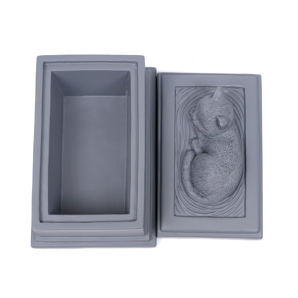 Gray square resin pet memorial urn open, showing empty interior and cat relief panel