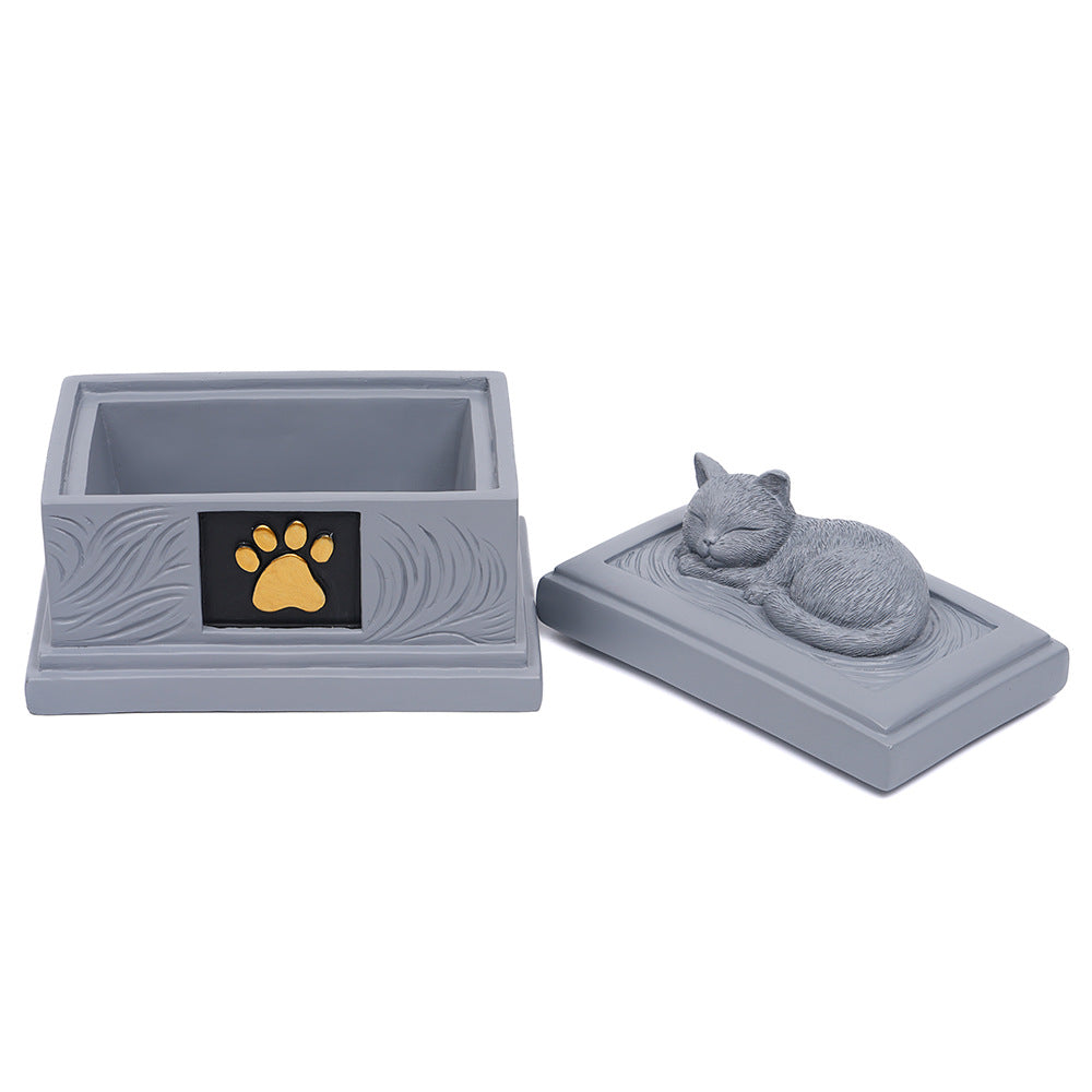 Gray resin pet memorial urn with open lid showing empty interior and gold paw emblem