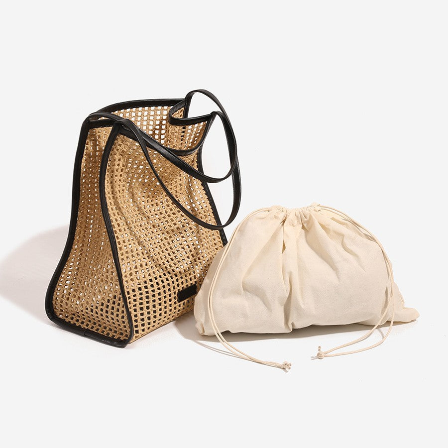 Woven straw tote bag with black straps and open top, with cream drawstring pouch