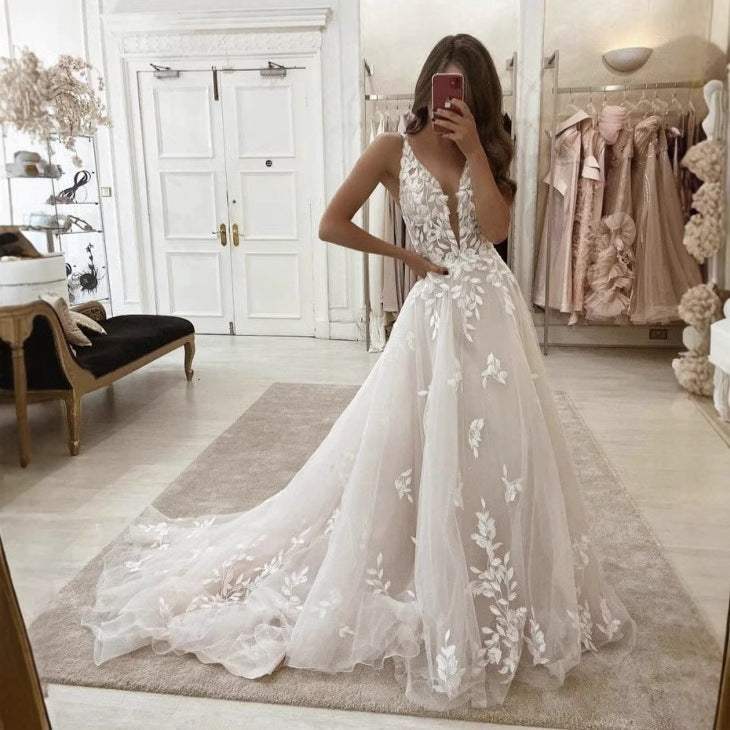 Ivory lace wedding gown with sleeveless V-neck, fitted waist, floral applique down skirt