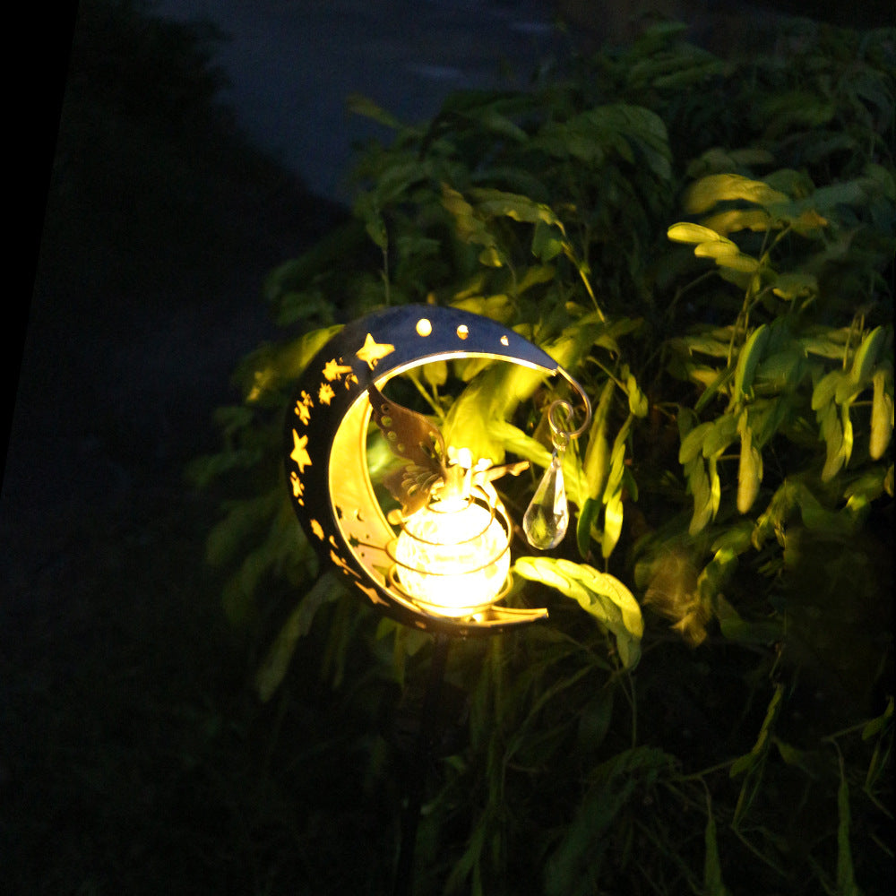 Outdoor solar moon garden lamp glowing gold with crescent fairy motif and glass globe