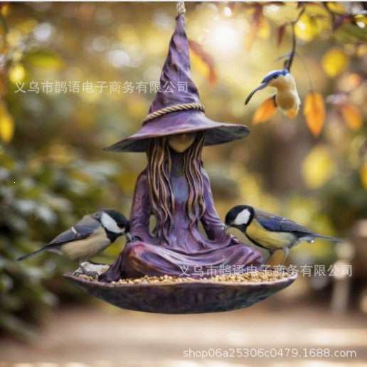 Purple witch bird feeder hanging from a rope with seated figure and three songbirds