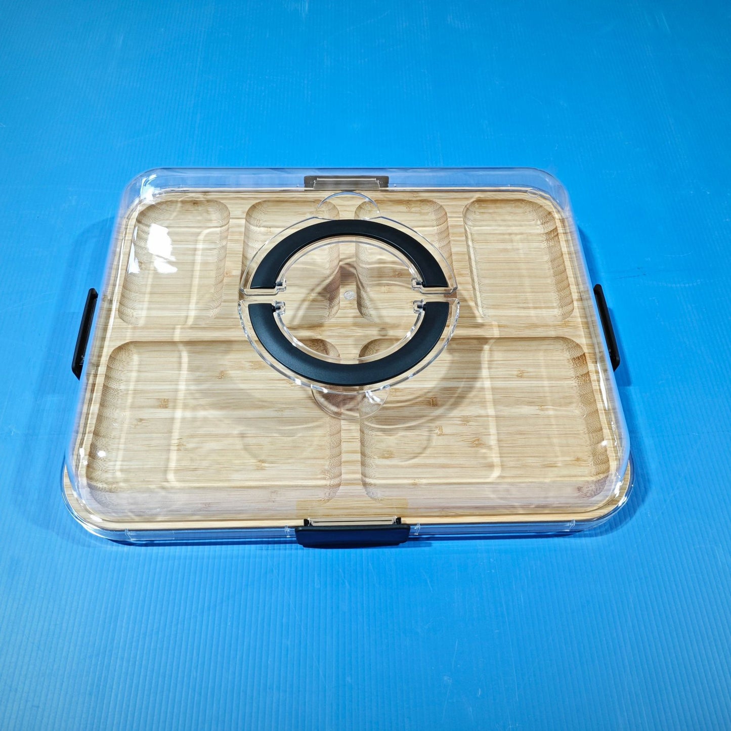 Bamboo charcuterie board with clear transparent lid, black rim and latch, top view