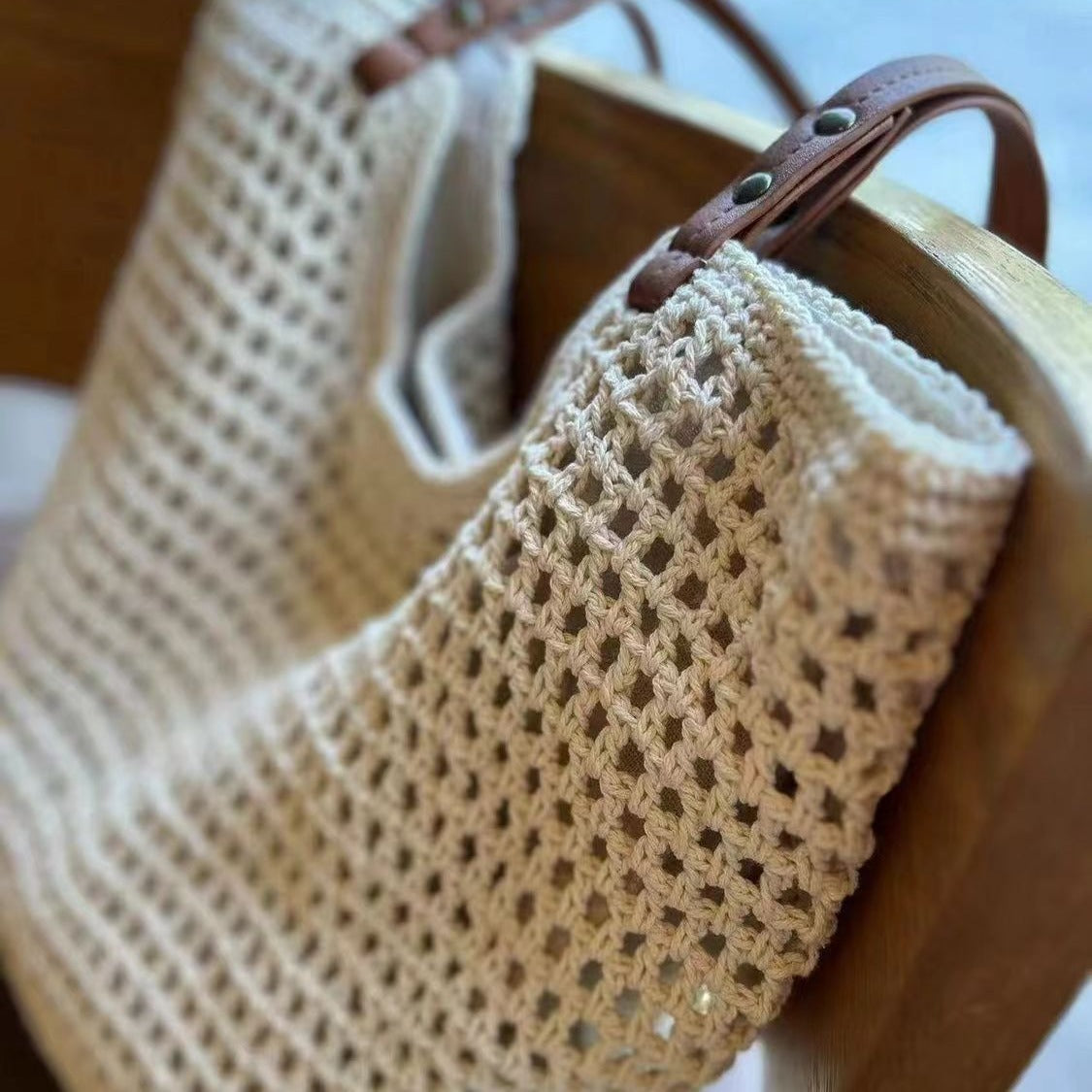 Off-white cotton mesh tote bag side detail with brown leather strap and metal rivets