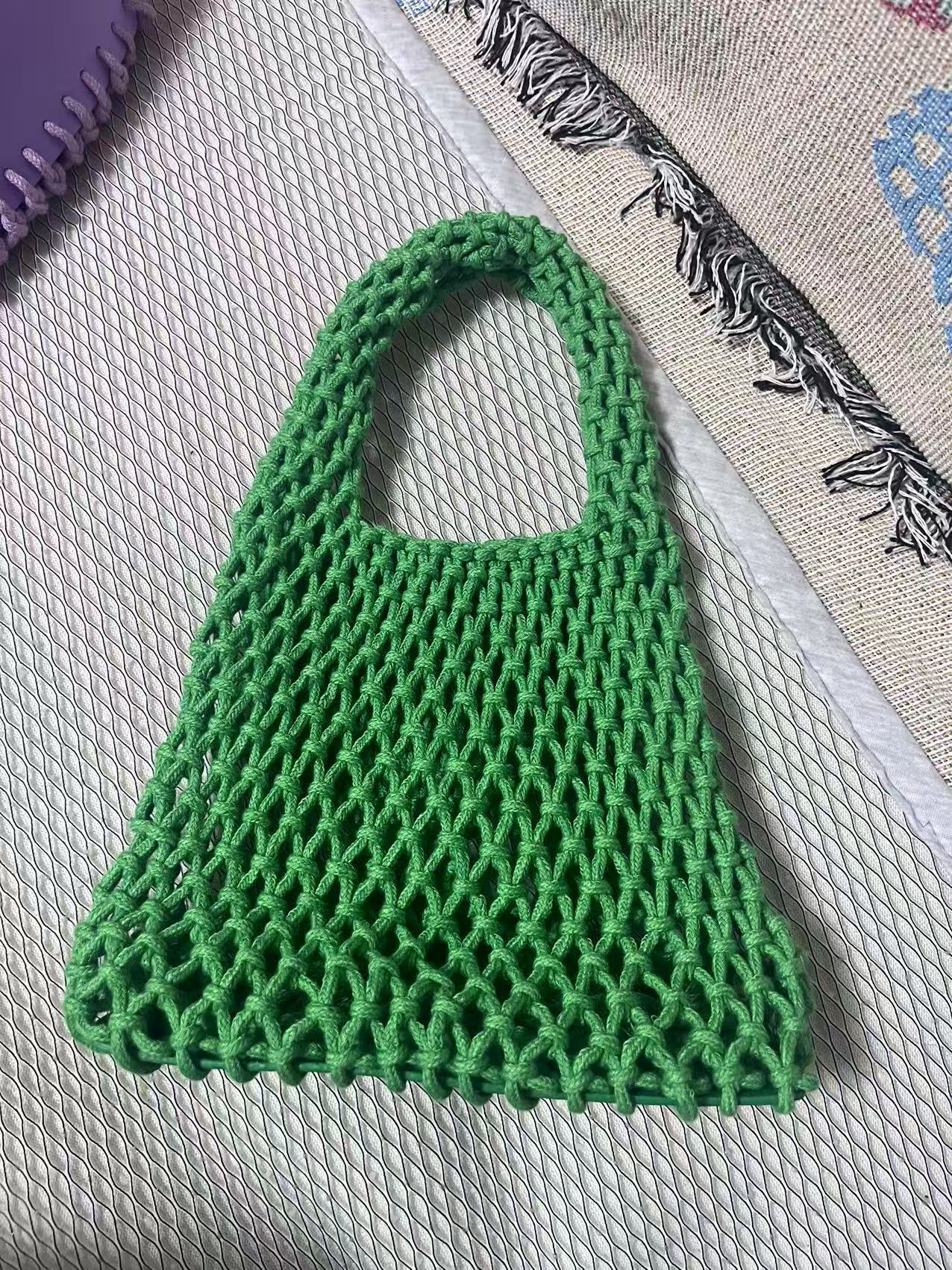Green woven cotton rope bucket bag with hollow net weave and loop handle.