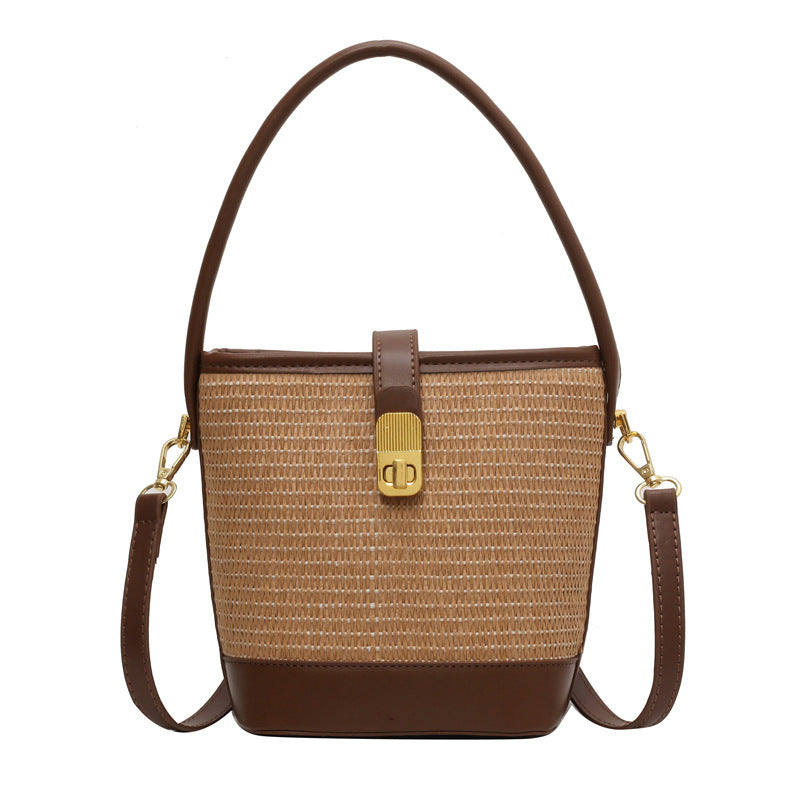 Beige woven bucket bag with brown leather trim, top handle, and side crossbody straps.