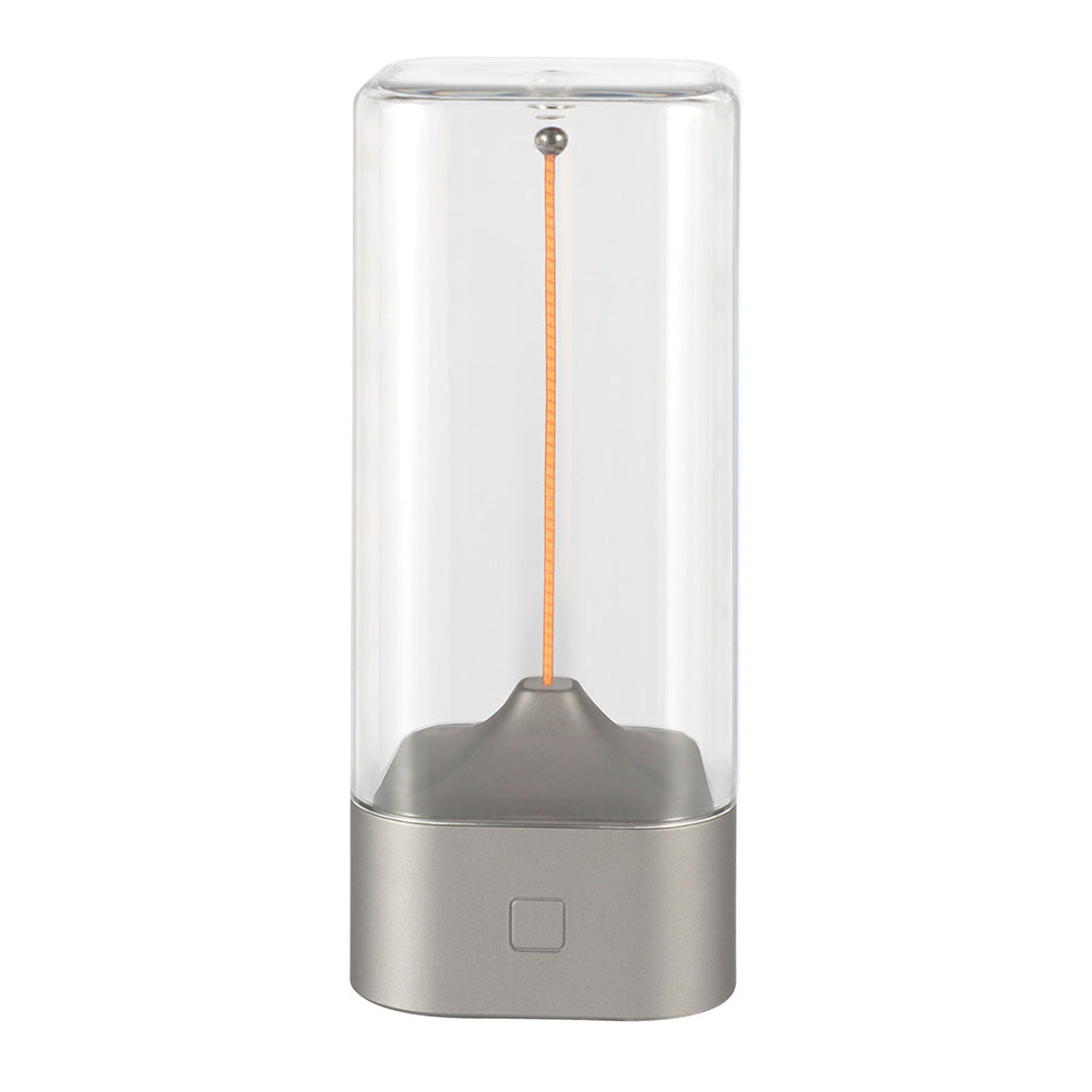 Rechargeable LED night light with clear glass cylinder and silver base, exposed warm filament